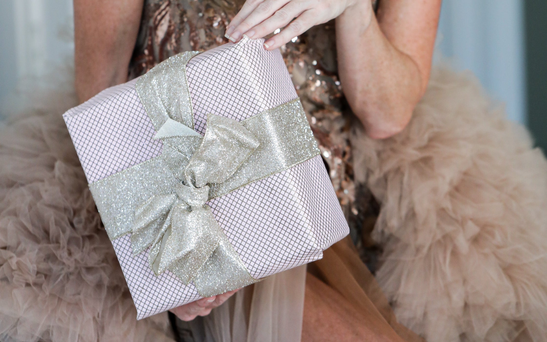 Woman holding a gift box with bow to camera