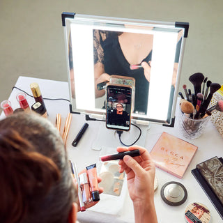 Woman holding makeup products while taking a virtual class 