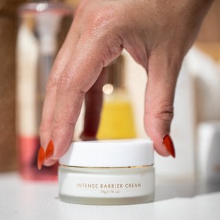 Hand unscrewing the top of Intense barrier cream moisturizer jar