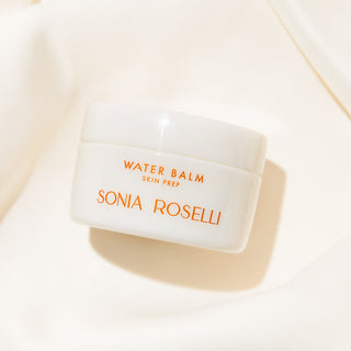 Water Balm jar laying on white silky backdrop 