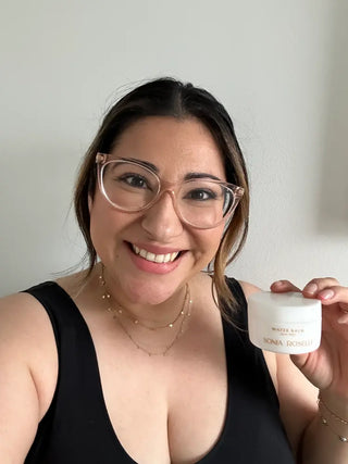 brunette with glasses holing a jar of water balm