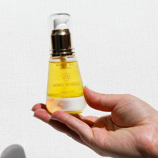 Water Oil being held out with a hand on white backdrop 