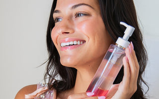 close up of woman holding japanese cleansing oil near face
