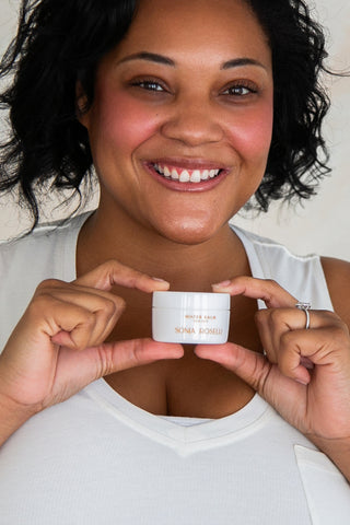 black woman holiding water balm smiling