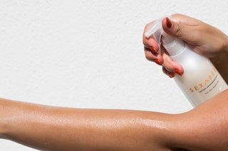Close-up image of Sonia Roselli exfoliation spray being applied to arms, set against a white background