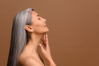 woman feeling her skin in tan background