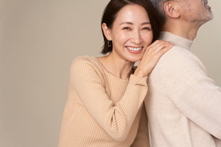 asian woman smiling wiht hand on mans shoulder.