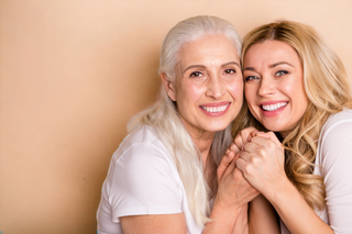 woman over 50 and daughter over 30 holding hands showing off great skin