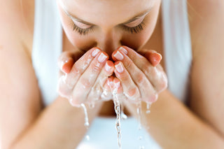 Woman with cupped hands slashing water onto face