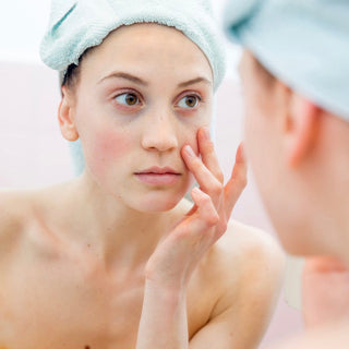Woman looking at her red skin in the mirror with concern