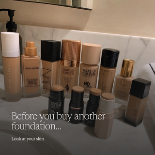 A collection of ten different foundation and concealer products arranged on a marble bathroom counter with a mirror behind them. The text overlay reads 'Before you buy another foundation.