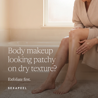 A woman in a beige waffle robe sits by a window, applying or showing a body makeup product on her leg. Large text reads, 'Body makeup looking patchy on dry texture? Exfoliate first.