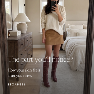 A woman takes a mirror selfie in a bedroom, wearing a cream knit sweater, a tan mini skirt, and dark burgundy knee-high boots with embossed floral detailing. Text on the image reads, 'The part you'll notice? How your skin feels after you rinse.