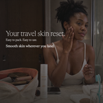 A woman in a white camisole sits in a bathroom setting, applying cream to her face. In the foreground, an open beige makeup bag and a white travel skin reset bottle are visible on a counter, with promotional text on the left.