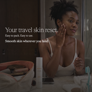 A woman in a white camisole sits in a bathroom setting, applying cream to her face. In the foreground, an open beige makeup bag and a white travel skin reset bottle are visible on a counter, with promotional text on the left.
