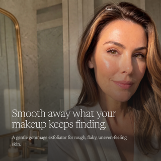 A close-up lifestyle shot of a woman with smooth, radiant skin wearing a soft white robe in a warm, elegant bathroom setting. Text on the left reads, 'Smooth away what your makeup keeps finding.