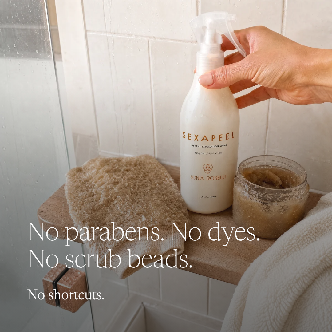 A hand holds a bottle of Nona Roselli Sexapeel Exfoliating Spray in a bathroom setting. The scene includes a wooden shelf with a beige scrubber, a jar of scrub, and a white towel, with text overlay reading 'No parabens.