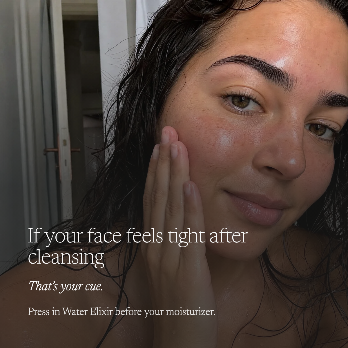 A close-up lifestyle shot of a woman with wet, damp skin touching her cheek, with overlaid text reading, 'If your face feels tight after cleansing / That's your cue. / Press in Water Elixir before your moisturizer.