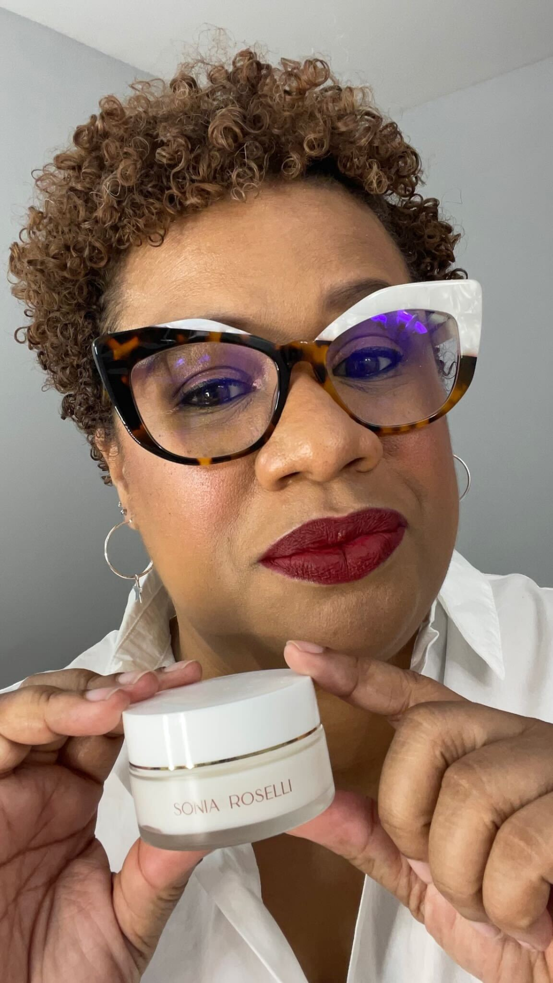 Woman holding Intense Barrier Cream up to the camera and smiling.