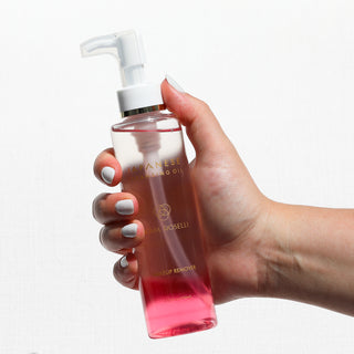 Japanese Cleansing Oil held up in hand on white background