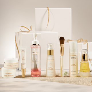 Collection of skincare products with a white gift bag on a neutral background