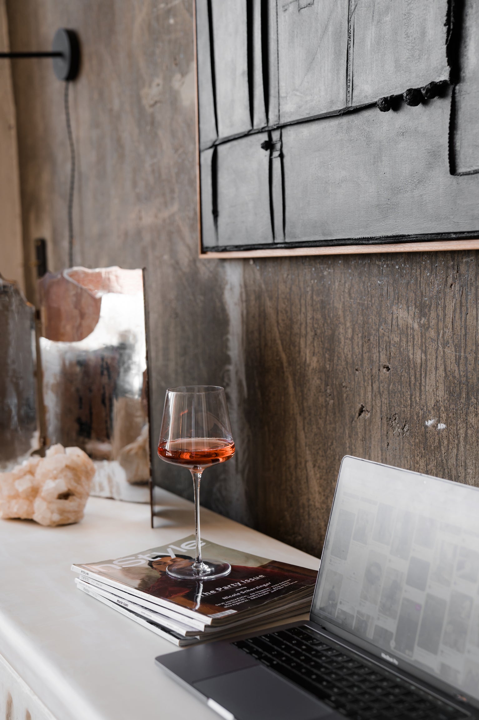 a glass of wine on fashion magazines and a computer