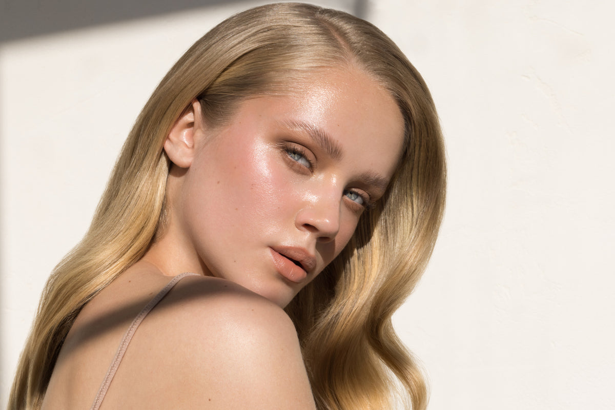 Woman with glowing skin looking into the camera over her shoulder. 