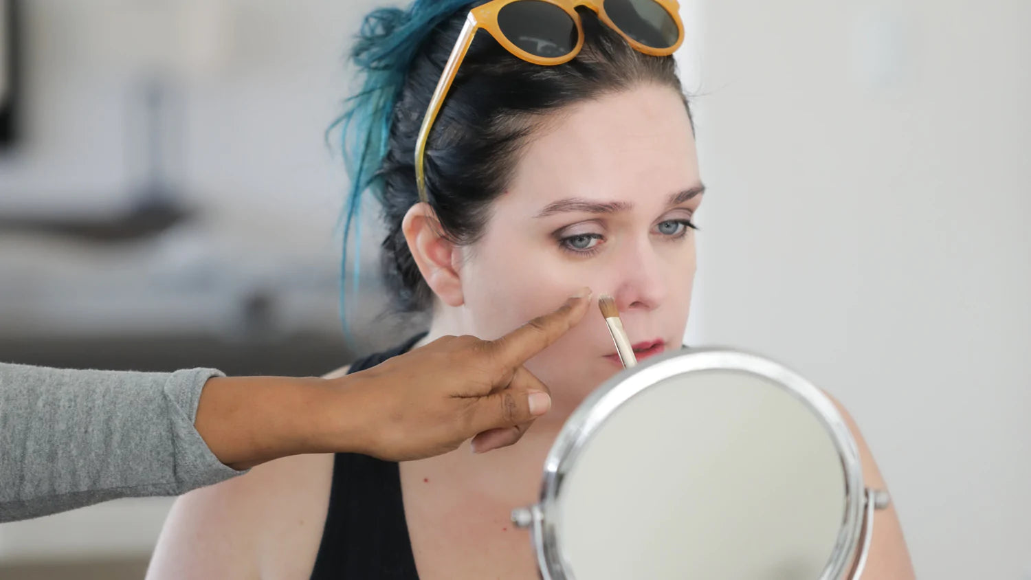 Woman looking in mirror while applying makeup.