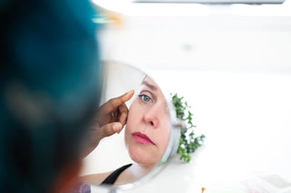 Woman looking in mirror while educator points to her eye.