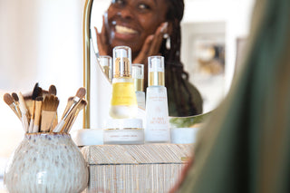 Woman looking in mirror smiling with her skincare.