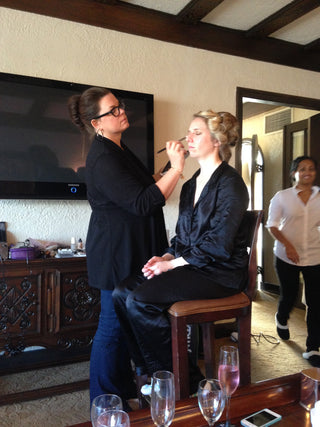 sonia applying makeup to client in room with people moving around