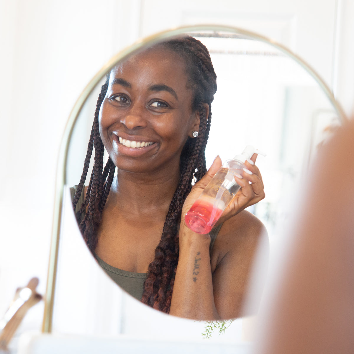 Woman looking in mirror holding Japanese Cleansing Oil 