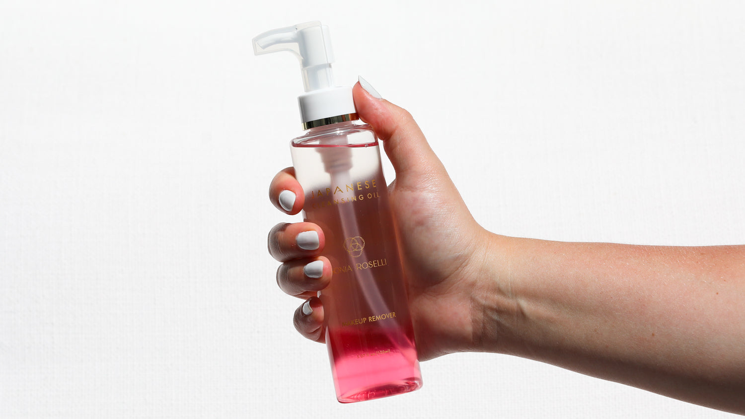 Hand with white finger nails holding Japanese Cleansing Oil 