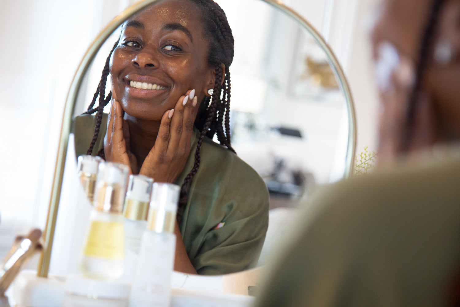 Woman with glowing skin applying product in the mirror