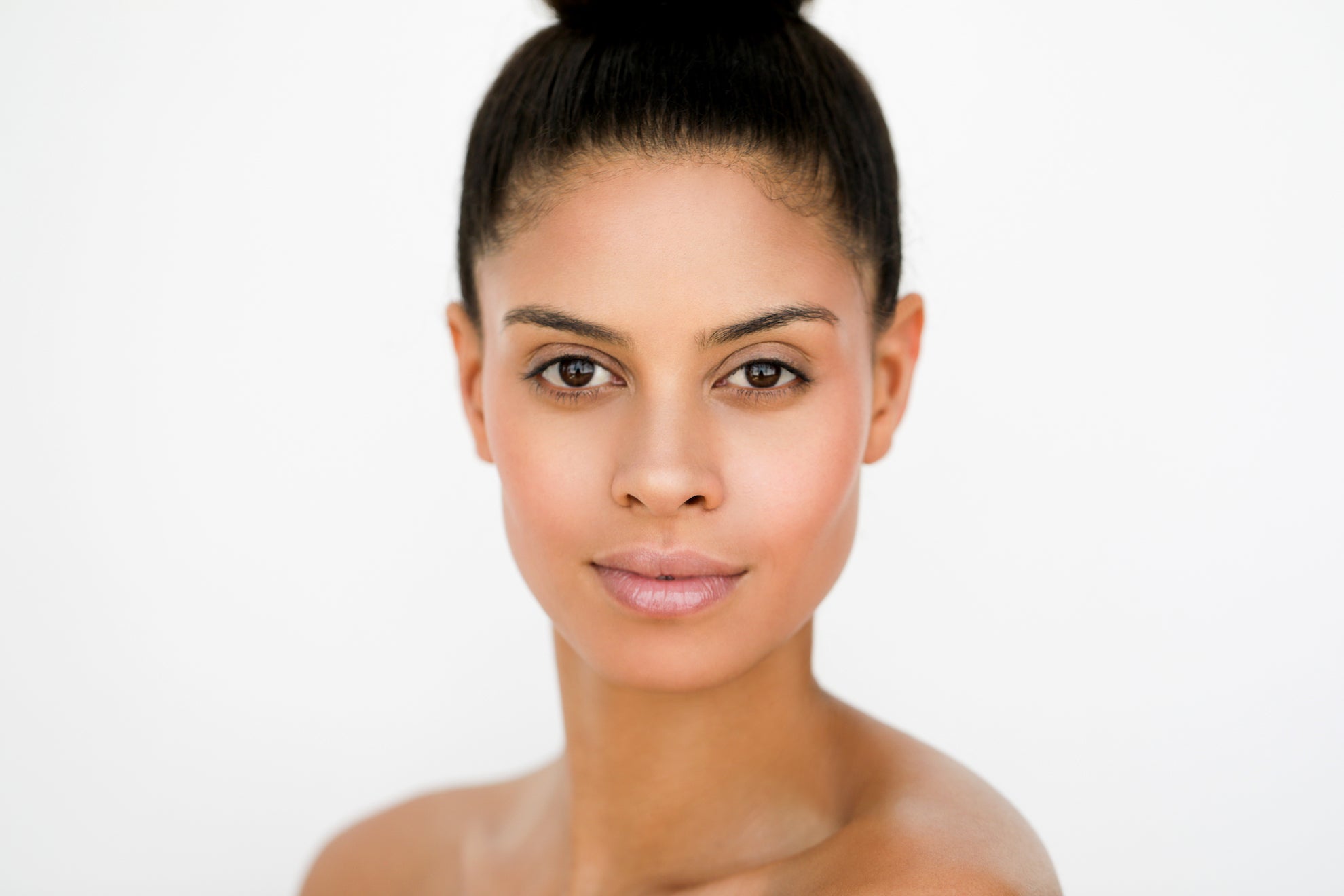 Woman with glowing skin in front of a white background.