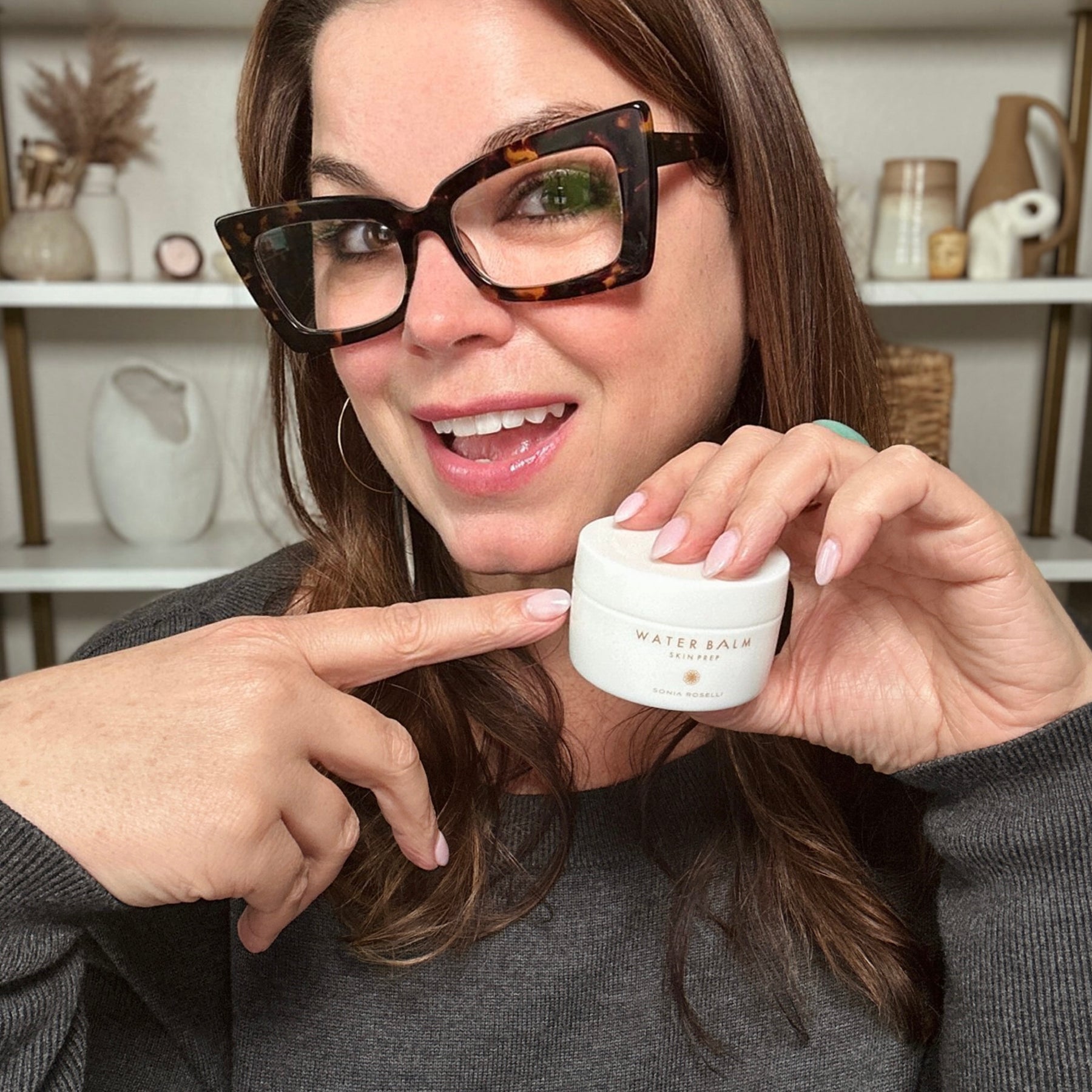 Sonia holding and pointing at a jar of Water Balm