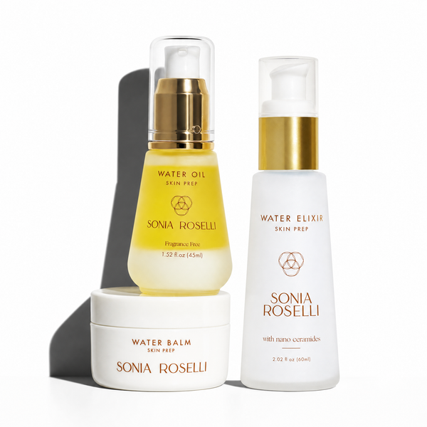 Three Sonia Roselli skincare products arranged on a white background: a Water Balm jar sitting underneath a Water Oil bottle, with a Water Elixir pump bottle to the right. The products are shown with gold caps and clear tops, with one bottle filled with pale yellow oil and the jar and right bottle in white.