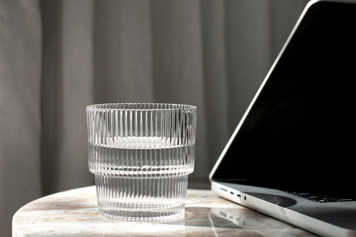 glass of water next to a laptop 