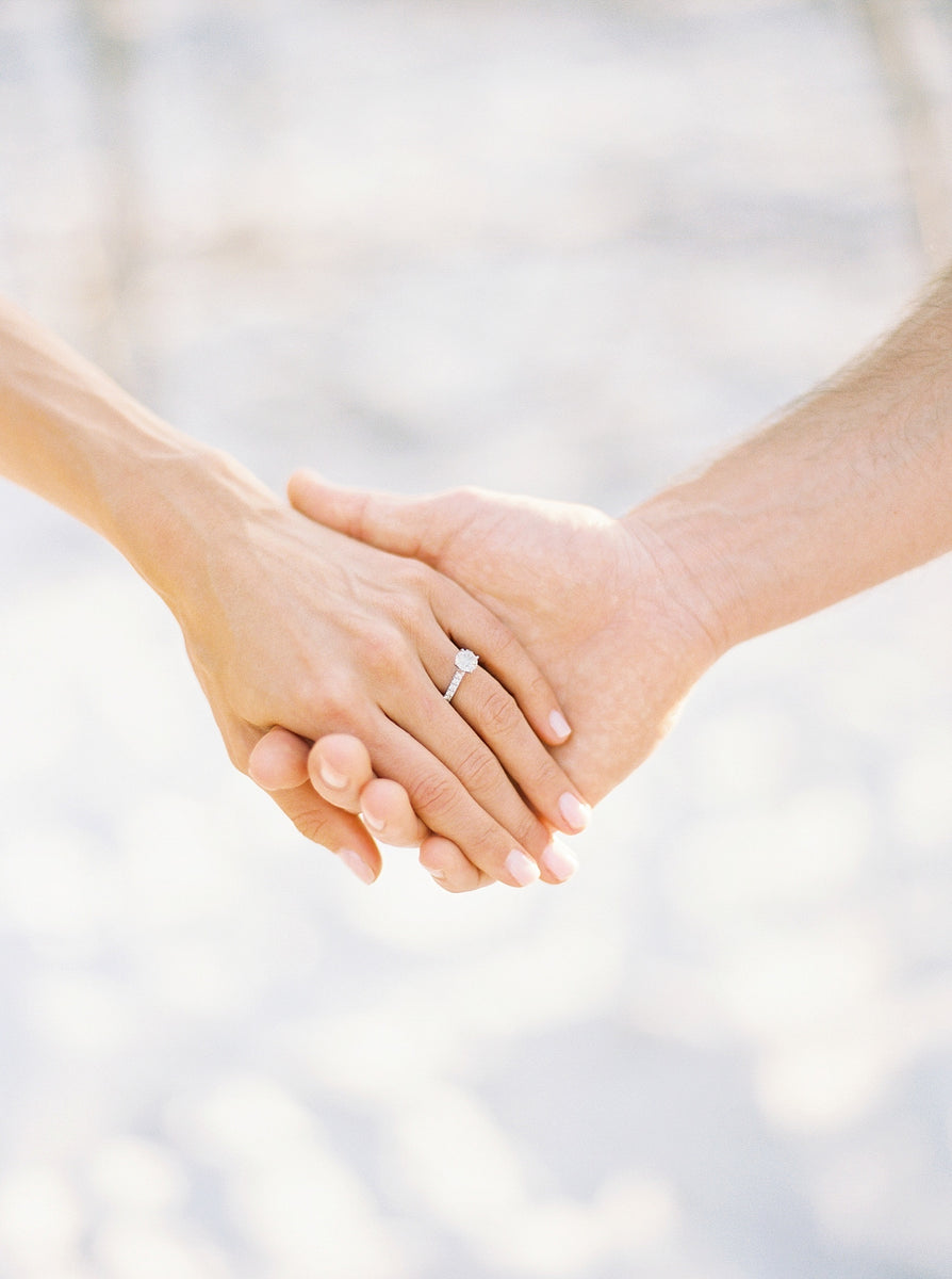 Woman's hand with wedding ring holding a man's hand.