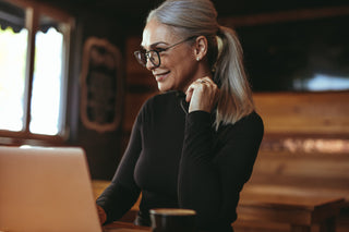 mature woman on computer with glasses in coffee shop