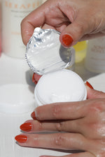 Close-up of hydrated hands removing the seal from a skincare moisturizer Water Balm, highlighting self-care and skin barrier hydration.