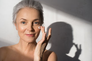woman applying moisturizer with light sunlight background.