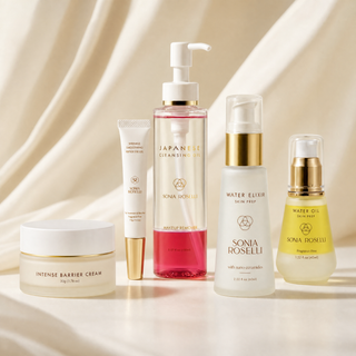 Five Sonia Roselli skincare products arranged together on a draped cream fabric background. The set includes a jar of Intense Barrier Cream, a white tube, a large pump bottle of Japanese Cleansing Oil with pink liquid, a white pump bottle labeled Water Elixir, and a yellow Water Oil bottle with gold detailing.
