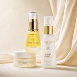 Three Sonia Roselli skincare products arranged on a soft cream fabric backdrop: a Water Oil serum bottle with a gold pump, a Water Elixir serum bottle with a white pump and gold band, and an Intense Barrier Cream jar. The products are clean, well-lit, and professionally styled.