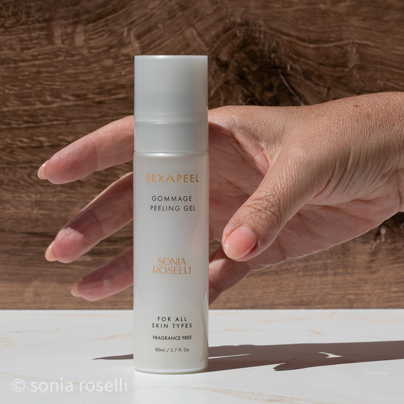 Hand holding a bottle of Sonia Roselli gommage peeling gel against a wooden background