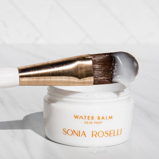 Skin Prep brush dipped in product propped up on Water Balm jar
