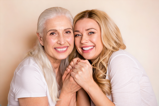 a women over 50 model with daughter holding hands cream showing off good skin