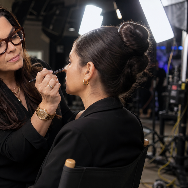 Makeup artist applying makeup to a model on a film set.