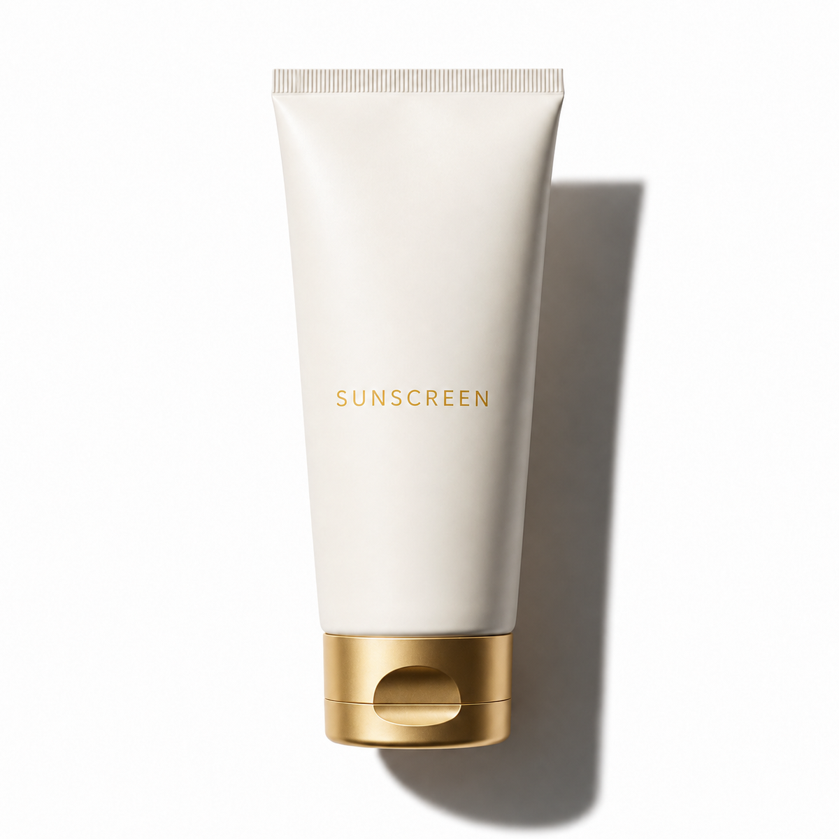 A white squeeze tube of sunscreen with a metallic gold cap and gold 'SUNSCREEN' text, photographed on a clean white background with a soft shadow.