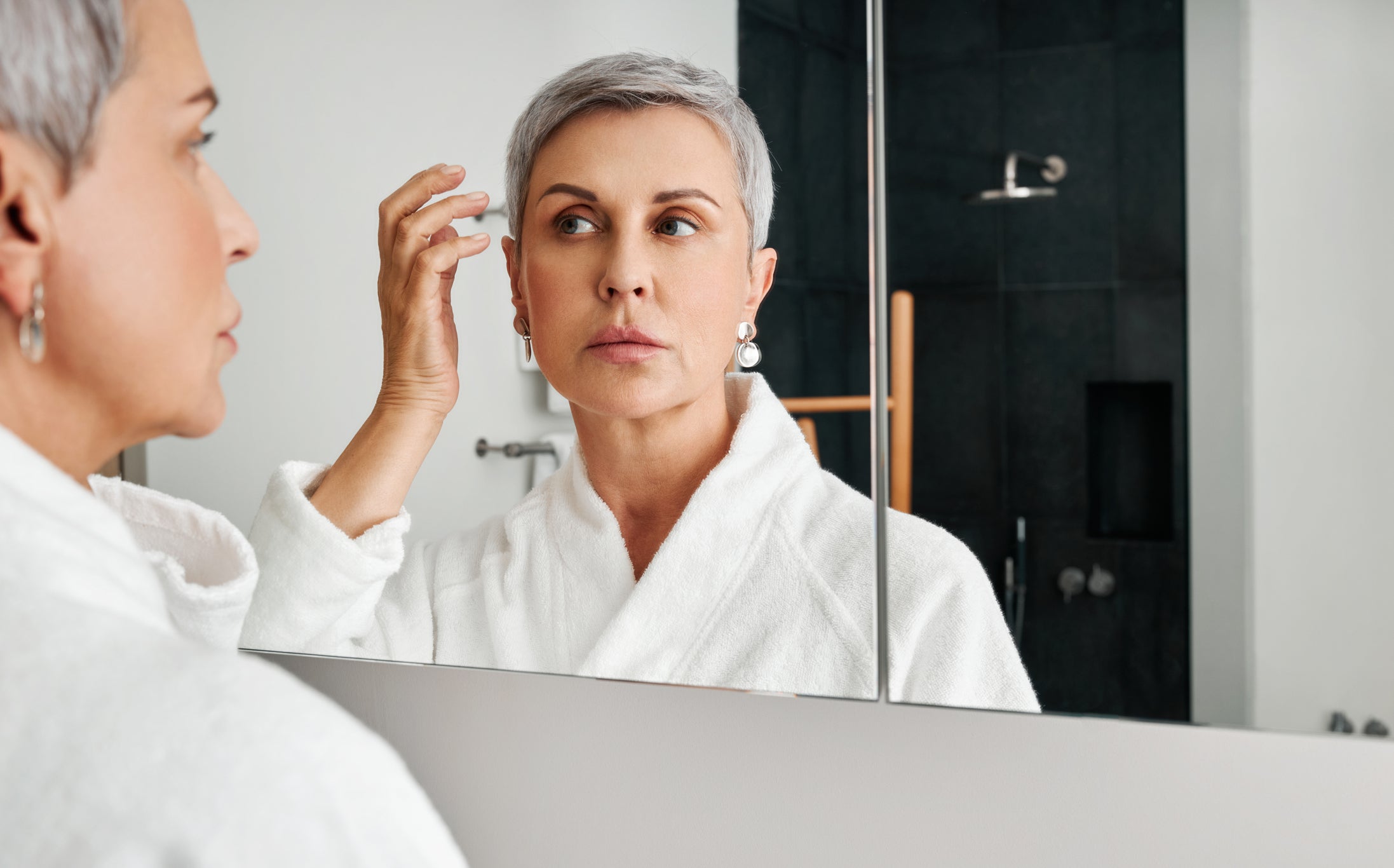 Woman looking in mirror at her face with dry skin